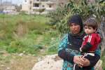 Khadra, refugiada siria, sostiene en brazos a su sobrino en el asentam...