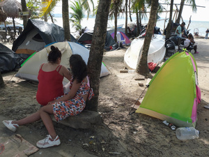 Familias acampan en la playa en Necoclí, Colombia, mientras esperan para cruzar la selva del Darién.