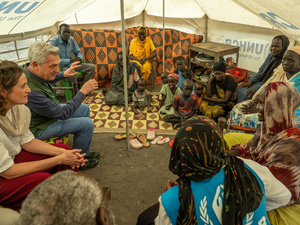 Dos trabajadores de ACNUR (uno de ellos es el Alto Comisionado, un hombre cano) charla con una familia sudsudanesa en un campamento de refugiados