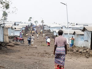 Varias personas caminan por el ondulado suelo seco de un campamento de desplazados internos