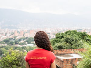 Una mujer de espaldas mirando a un paisaje urbano desde un mirador.