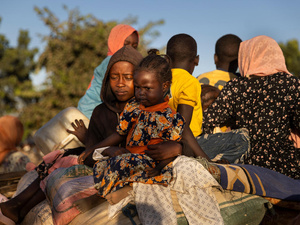 Un grupo de mujeres y niños viajando en parte trasera de una carreta.