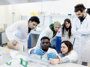 Un grupo de estudiates en bata médica haciendo pruebas en un laboratorio.