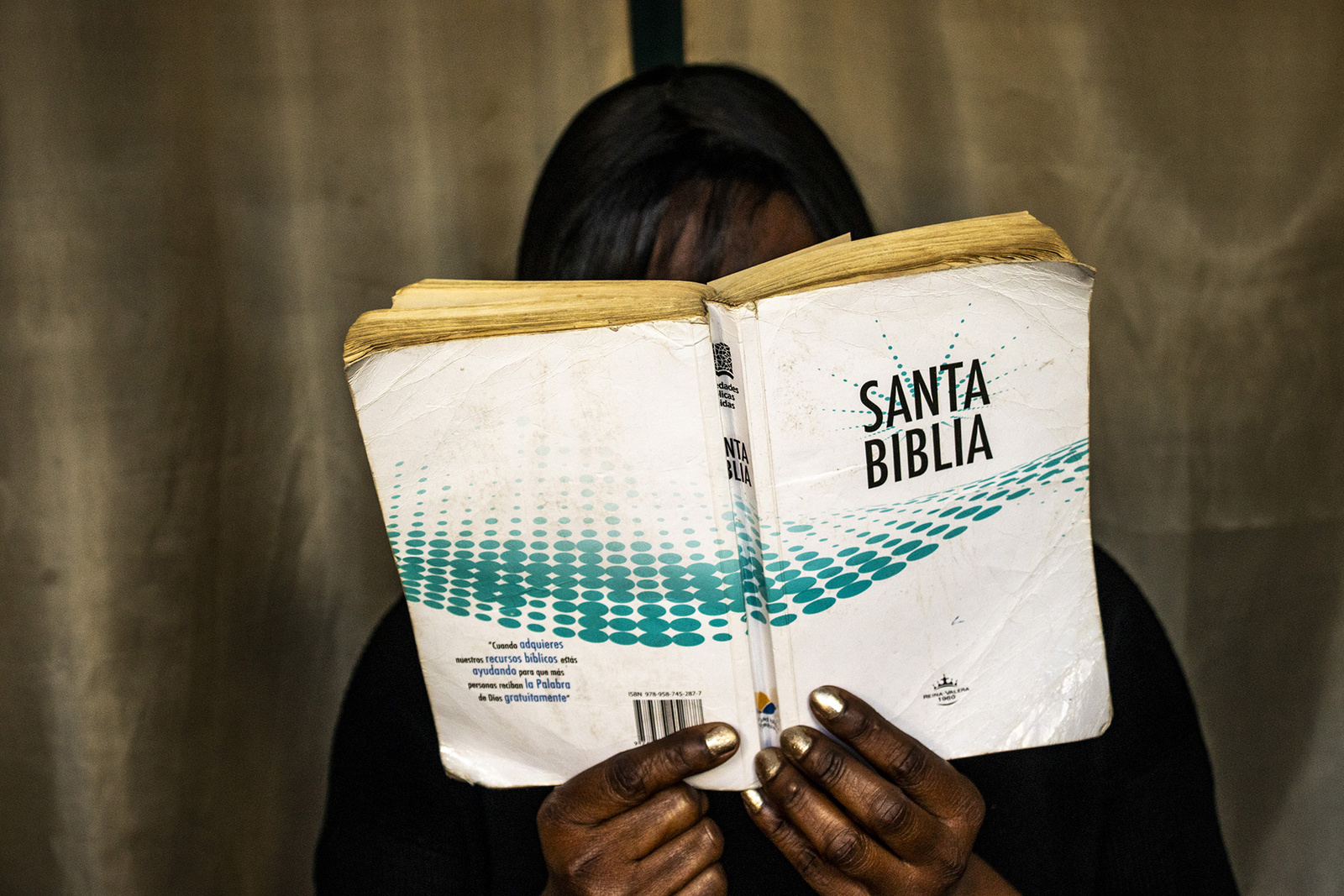 Una mujer fotografiada mientras lee la Santa Biblia sin mostrar su cara por motivos de protección.