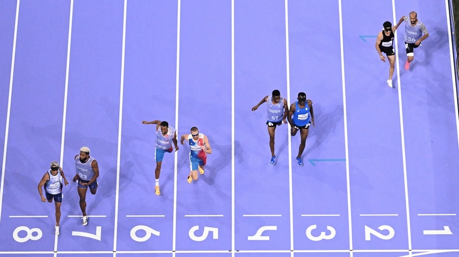 Guillaume Junior Atangana (terceiro à direita) e seu guia Donard Nyamjua (quarto à direita) cruzam a linha em terceiro lugar na final masculina dos 400m T11 no Stade de France, em Paris.