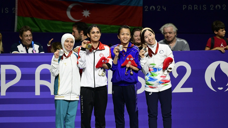 Zakia Khudadadi (última à direita) segura sua medalha de bronze ao lado de seus colegas medalhistas na entrega de medalhas do taekwondo K44 -47kg em Paris.