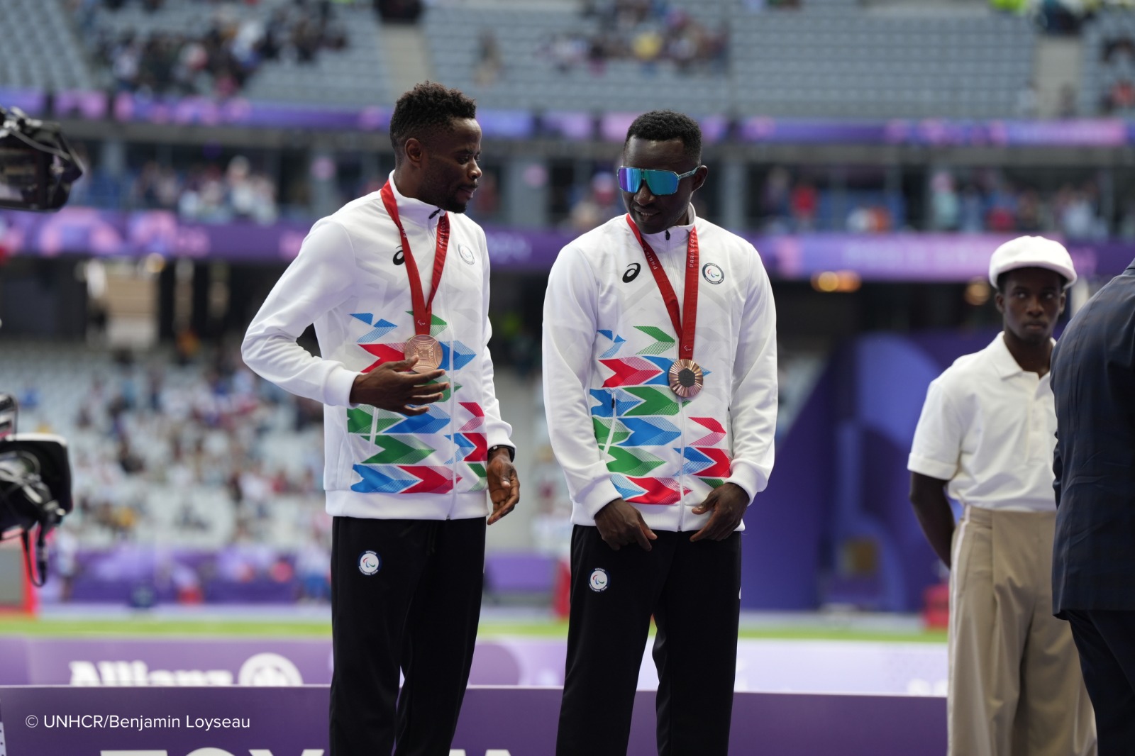 Guillaume Junior Atangana e seu guia Donard Nyamjua no pódio paralímpico, após receberem a medalha de bronze.