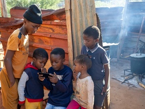 Crianças na zona rural da África do Sul se reúnem em torno de um celular