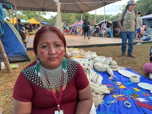 Mulher indígena Warao está sentada junto ao seu artesanato exposto para o público em uma feira