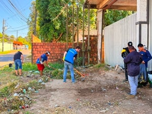Participantes das Brigadas Ecológicas realizam mutirão de limpeza em espaço urbano, utilizando ferramentas para remover resíduos e vegetação acumulada.