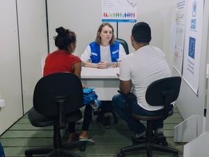 Refugiados em mesa em entrevista com funcionária do ACNUR