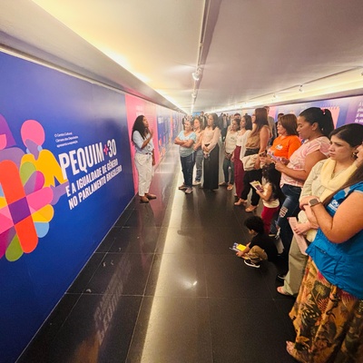 Mulheres refugiadas acompanhadas da equipe do ACNUR recebe explicação da guia da exposição