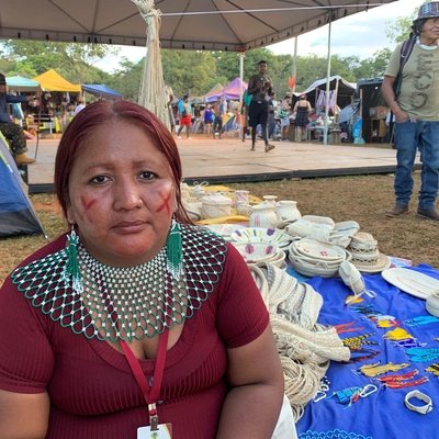 Mulher indígena Warao está sentada junto ao seu artesanato exposto para o público em uma feira