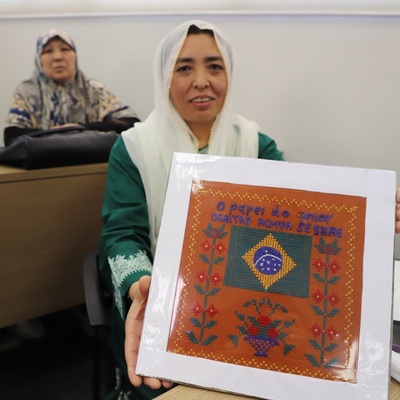 Mulher afegã mostra quadro com bordado feito durante o curso