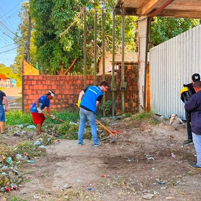 Participantes das Brigadas Ecológicas realizam mutirão de limpeza em espaço urbano, utilizando ferramentas para remover resíduos e vegetação acumulada.