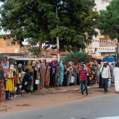Famílias recentemente deslocadas de El Fasher fazem fila para distribuição de alimentos ao lado de moradores de longa data em Omdurman, a segunda maior cidade do Sudão. 