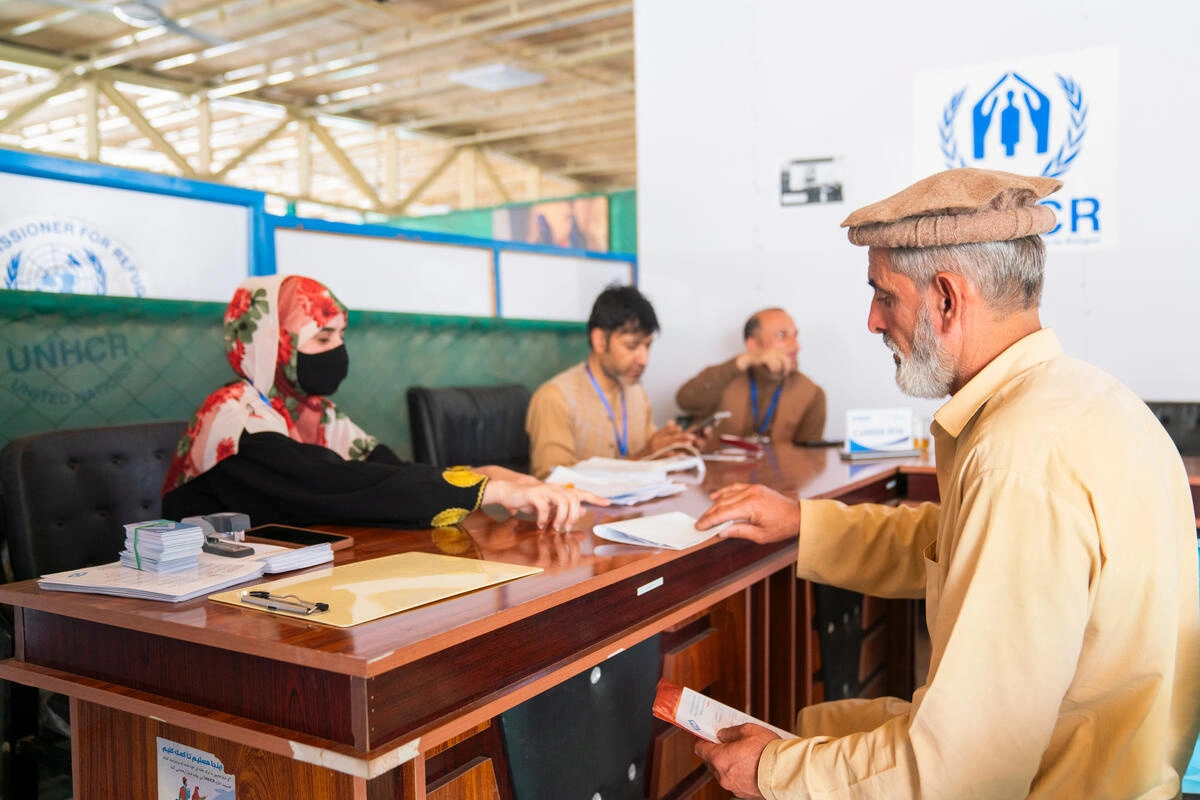 O afeg&atilde;o Ezatullah recebe a documenta&ccedil;&atilde;o de um membro da equipe em um centro do ACNUR em Samarkhail antes de receber um modesto apoio financeiro e outras formas de assist&ecirc;ncia