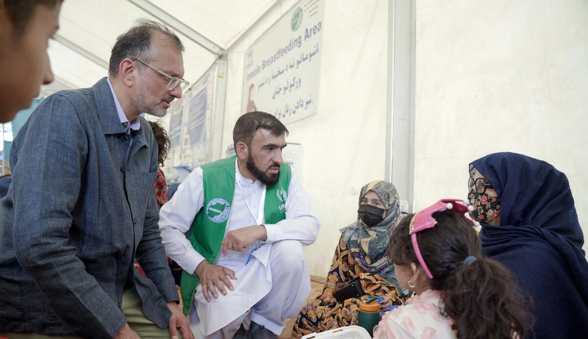 O representante do ACNUR no Afeganist&atilde;o, Arafat Jamal (&agrave; esquerda), e um membro da equipe do parceiro local Wadan conversam com Asma (&agrave; direita) em uma instala&ccedil;&atilde;o de recep&ccedil;&atilde;o perto da fronteira em Torkham