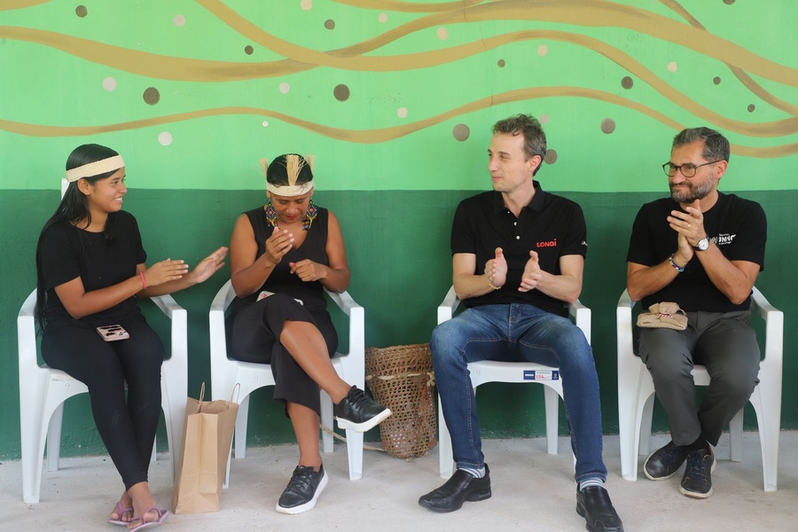 Quatro pessoas sentadas frente a uma parede colorida aplaudem e sorriem