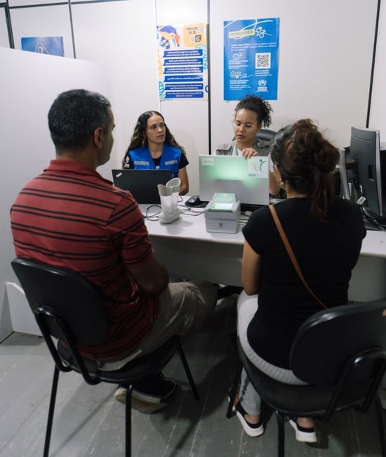 Funcionária do ACNUR e parceiro atendem pessoas refugiadas