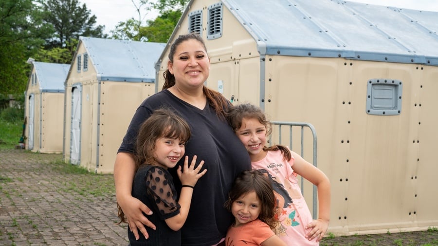 Mãe com 3 filhas crianças em frente a casa emergencial disponibilizada pelo ACNUR no Rio Grande do Sul após enchentes que devastaram o estado.