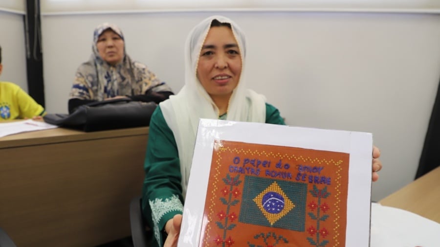 Mulher afegã mostra quadro com bordado feito durante o curso