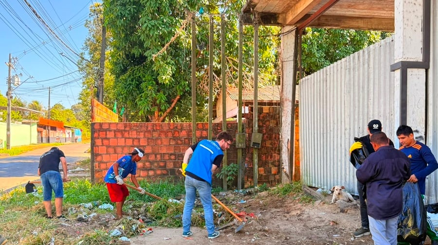 Participantes das Brigadas Ecológicas realizam mutirão de limpeza em espaço urbano, utilizando ferramentas para remover resíduos e vegetação acumulada.