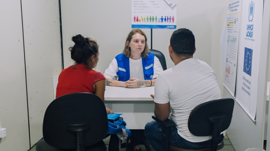 Refugiados em mesa em entrevista com funcionária do ACNUR