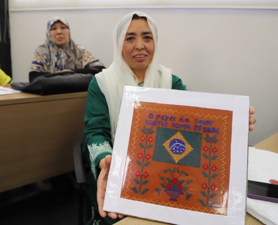 Mulher afegã mostra quadro com bordado feito durante o curso