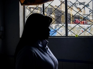 Mujer en contra luz tras un ventana 