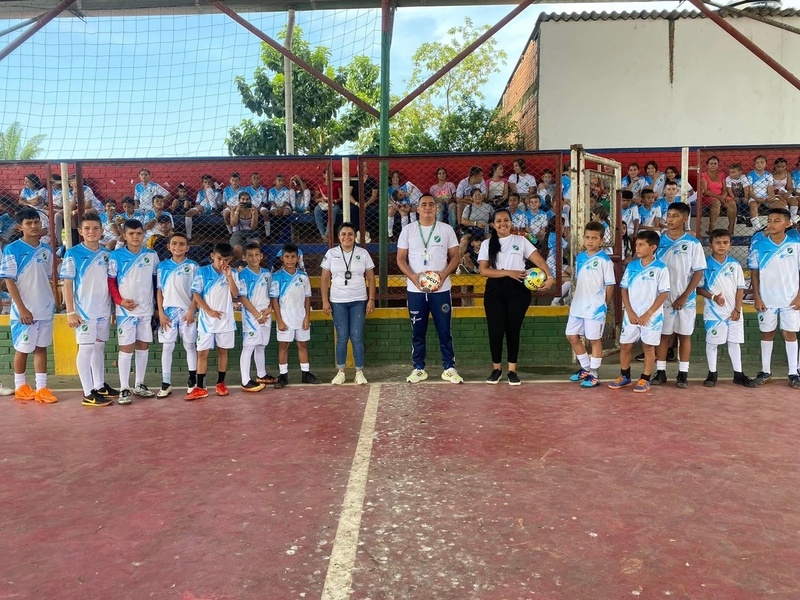 Un equipo de fútbol de niños y dos personas adultas, una mujer y un hombre joven 