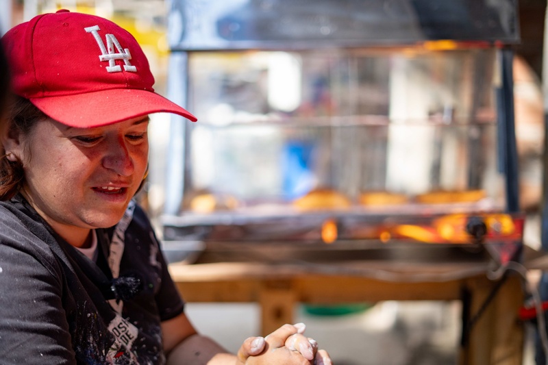 Artista Karina de perfil con gorra roja en el fondo se ven panes 
