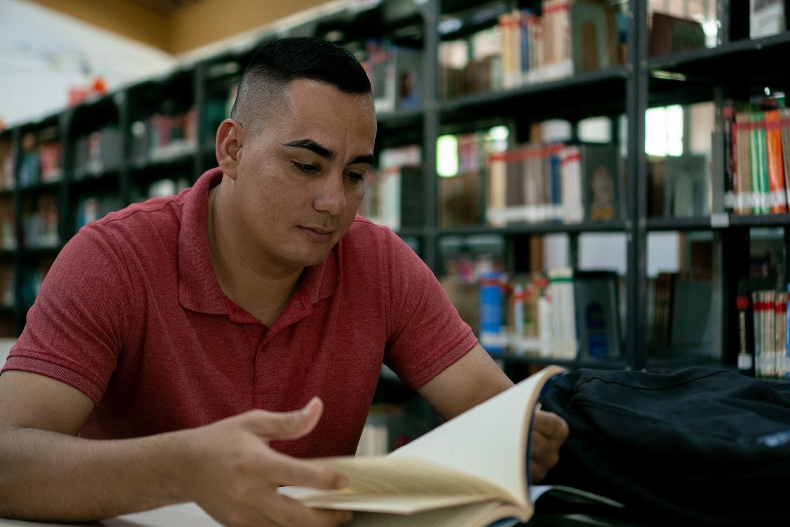 Joven hombre lee un libro en una biblioteca 