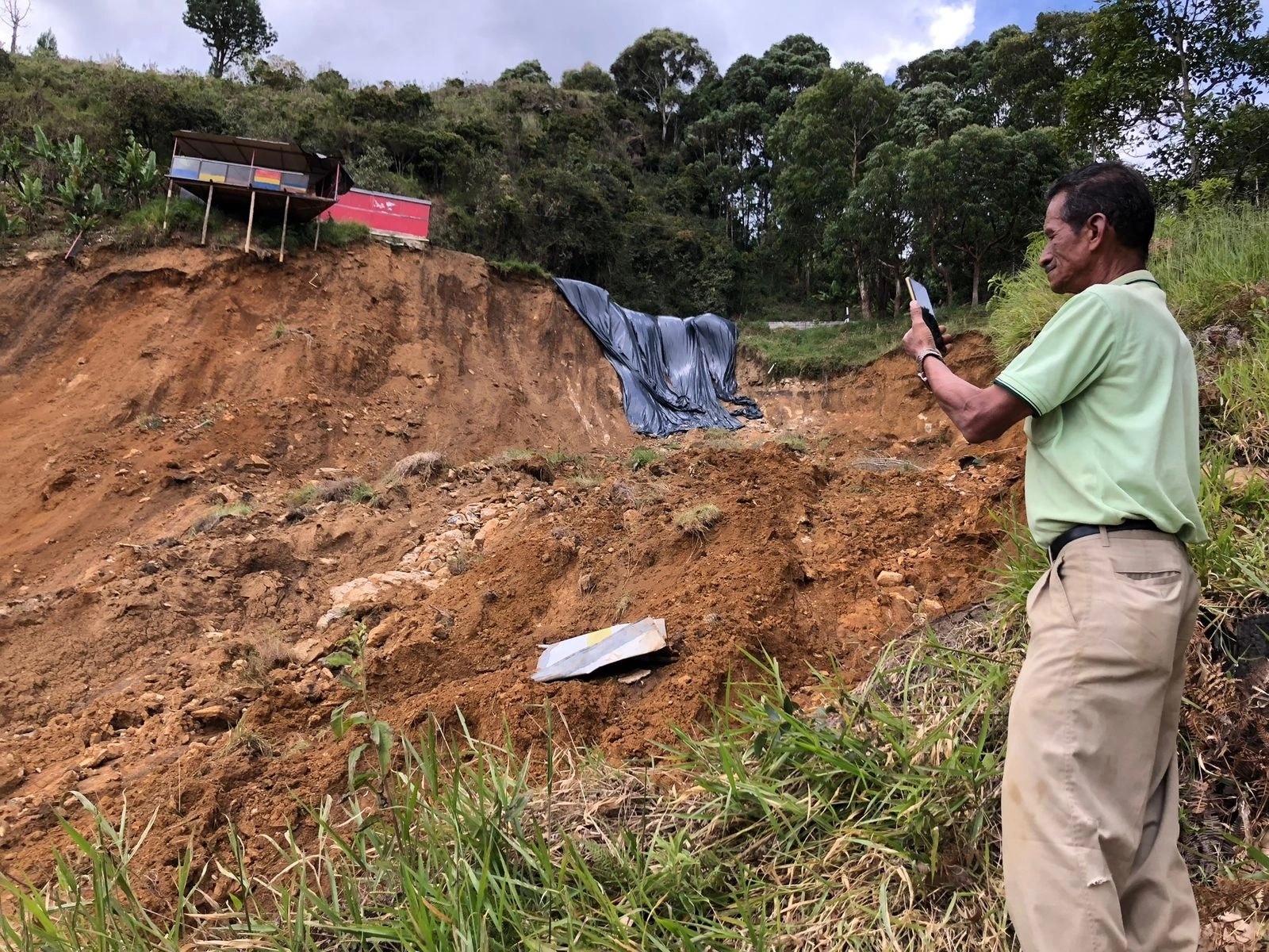 Hombre toma una foto un deslizamiento de tierra que amenaza de llevarse un casa 