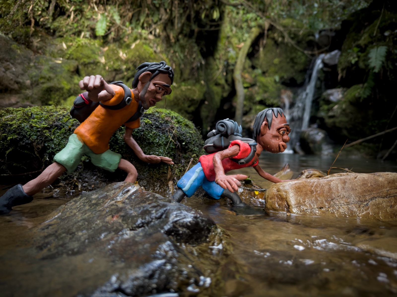 Figuras en plastilina de dos hombres cruzando un río 