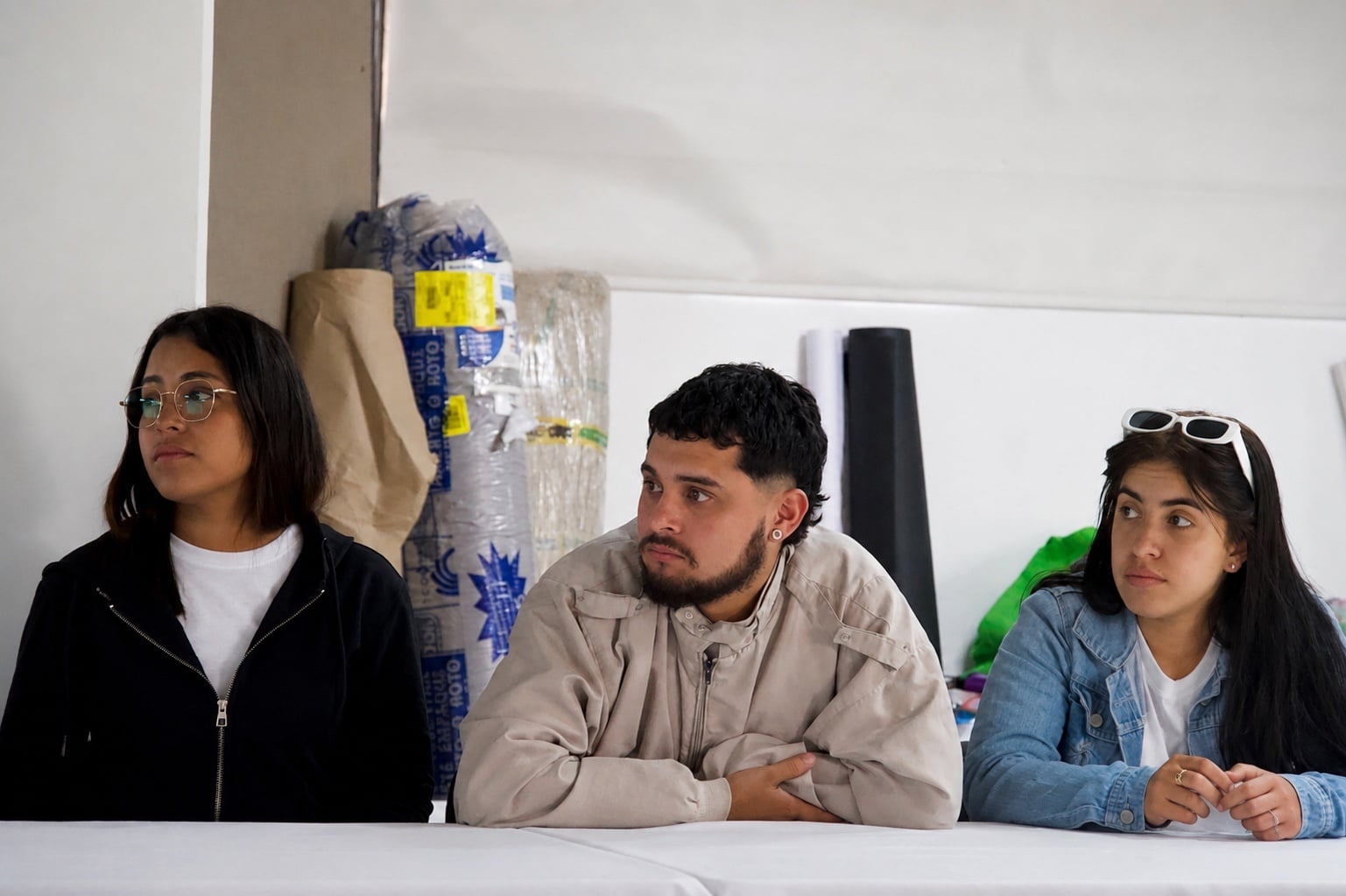 Dos jóvenes mujeres y un hombre en mesa de trabajo 