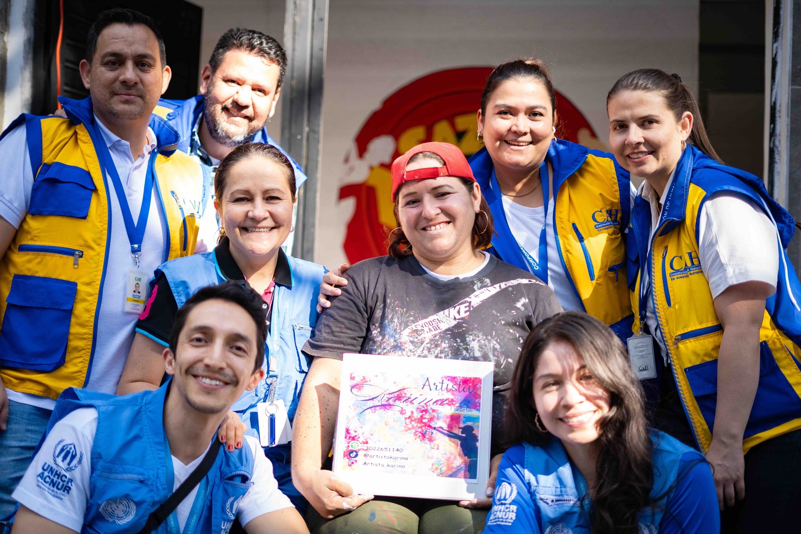 Karina con una sonrisa acompañada de hombres y mujeres con chalecos azules de la ONU