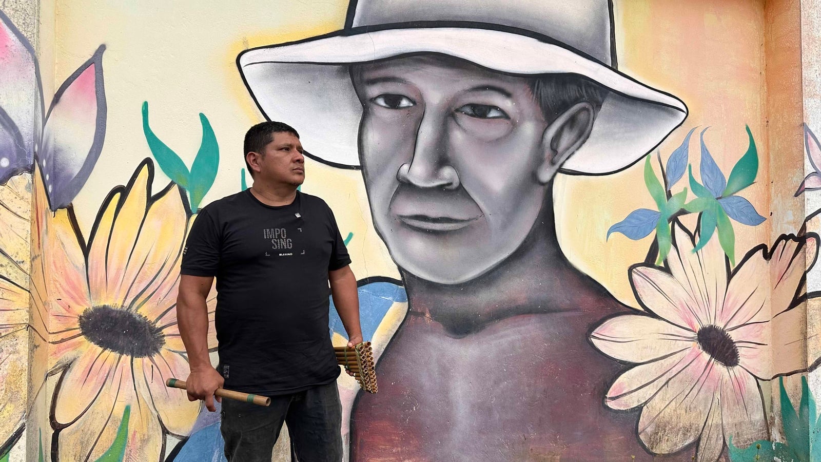 Docente de música frente aun mural artístico de la escuela tradicional del resguardo Yanacona