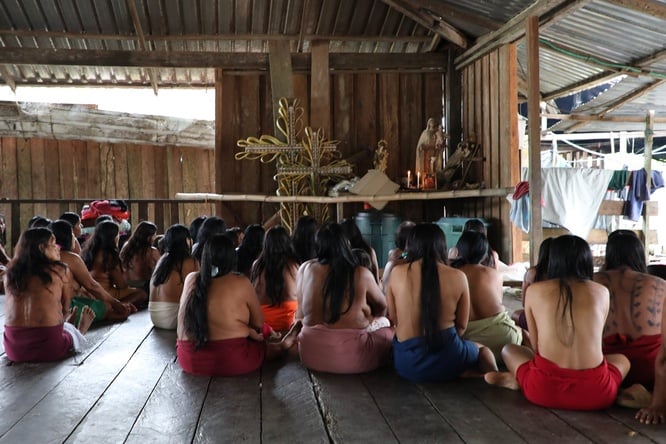 Mujeres Wounaan de espaldas frente a imágenes religiosas