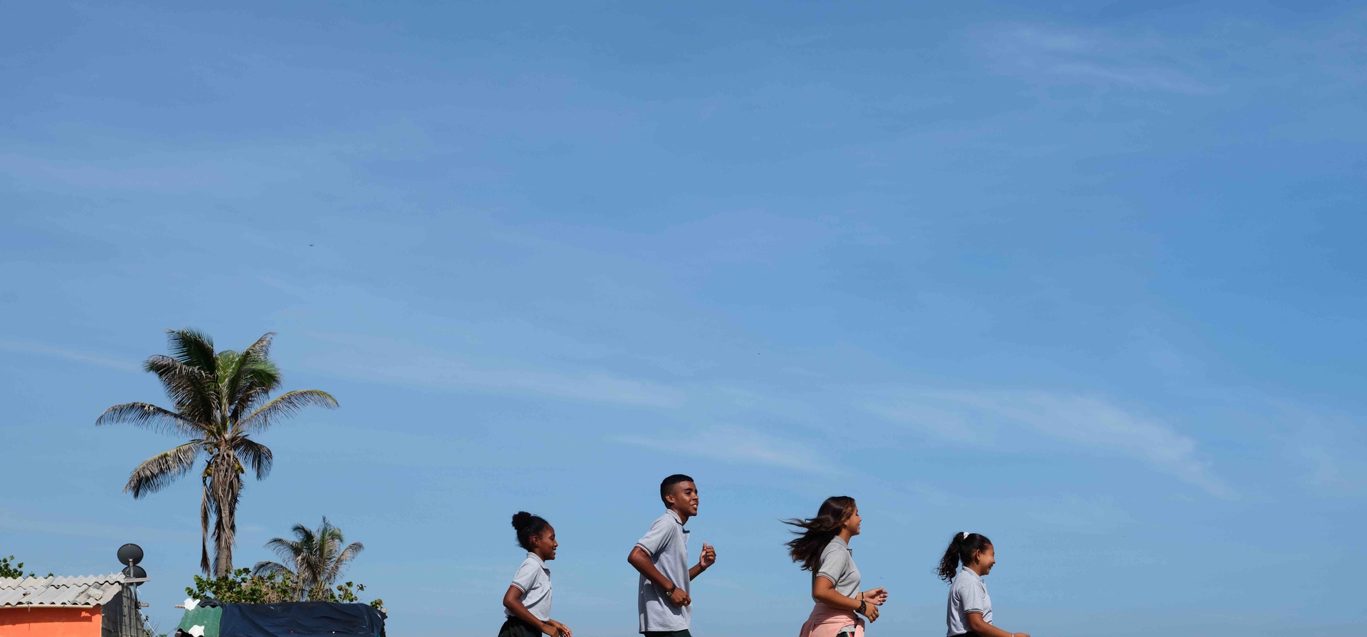 Tres adolescentes mujeres y un hombres corren en un espacio escolar