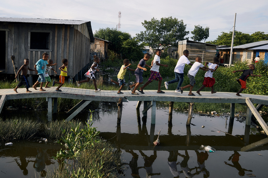 Niñas y niñas juega en puente en el asentamiento de personas desplazadas internamente, Pescadores I y II, Apartadó, Colombia.