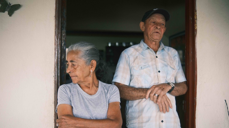 Un hombre y una mujer adultos mayores en una puerta de la casa. Pareja de personas desplazadas internamente.