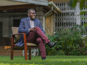 Un hombre sonriente sentado en una silla en un jardín