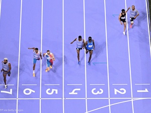 Vista aérea de cuatro parejas de corredores acercándose a la meta de una pista de atletismo de color morado con número y líneas blancas