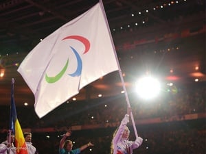 Una joven mujer lleva la bandera del IPC en un estadio iluminado.
