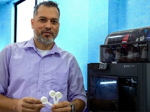 Un hombre posa al lado de una impresora 3D.