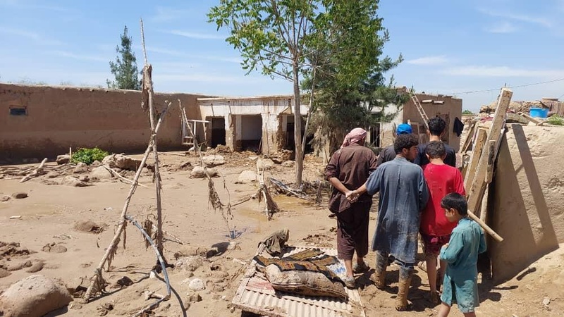 Un grupo de personas cerca de unos escombros en una zona afectada por inundaciones.