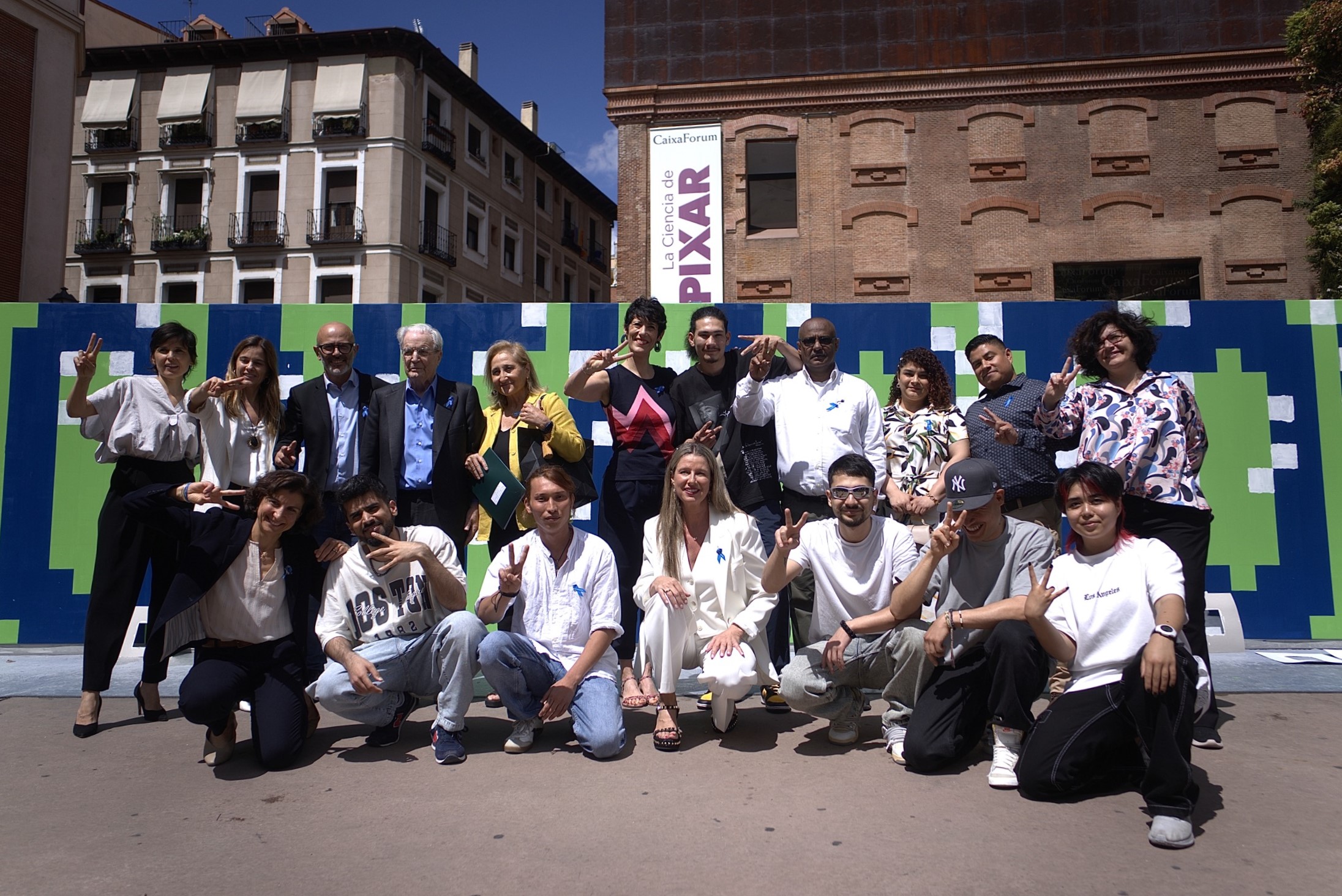 Autoridades y participantes en el evento de ACNUR con motivo del Día Mundial del Refugiado posan frente al mural solidario de Boa Mistura.
