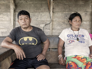 Una pareja de mediana edad sentada frente a una casa de madera.