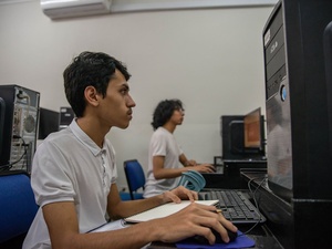 Un joven sentado en un escritorio trabaja con una computadora.